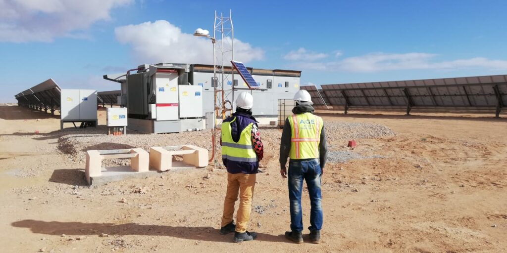 Deux techniciens d'Africa Green Energy devant un poste onduleur d'une centrale du programme NOOR PV1 au Maroc