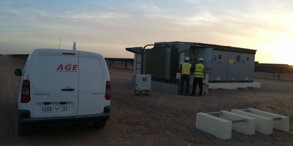 Deux techniciens d'Africa Green Energy devant un poste onduleur d'une centrale du programme NOOR PV1 au Maroc